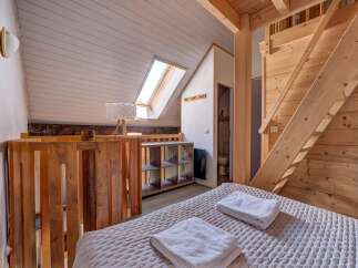 Experience cozy living in this charming loft bedroom, featuring a comfortable bed adorned with fresh white towels.