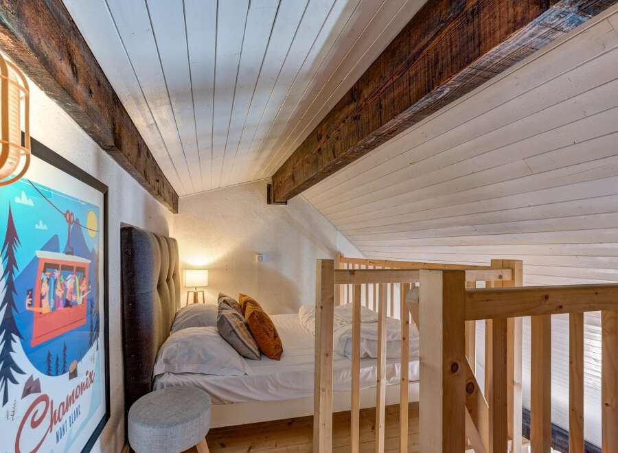 Experience cozy living in this charming attic bedroom, featuring exposed wooden beams and a sloped ceiling for a unique architectural touch.