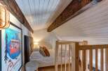 Experience cozy living in this charming attic bedroom, featuring exposed wooden beams and a sloped ceiling for a unique architectural touch.