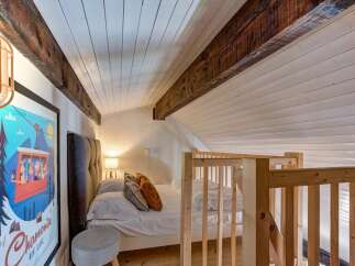 Experience cozy living in this charming attic bedroom, featuring exposed wooden beams and a sloped ceiling for a unique architectural touch.