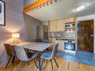 This charming dining area and kitchen space features a rustic wooden dining table with four upholstered chairs, perfect for intimate meals.