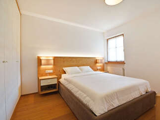 Experience comfort and style in this beautifully appointed bedroom, featuring a plush bed with crisp white linens and a warm wooden headboard.