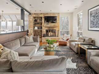 Experience luxury living in this stunning mountain retreat, featuring a grand stone fireplace as the centerpiece of the living room.