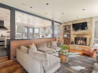 Experience luxury mountain living in this stunning home featuring a spacious sectional sofa perfect for cozy evenings by the stone fireplace.