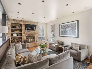 Experience luxury living in this stunning mountain retreat, featuring a grand stone fireplace as the centerpiece of a spacious living area.