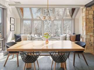 Experience breathtaking mountain views from this stunning dining area, featuring a large wooden table perfect for gatherings.