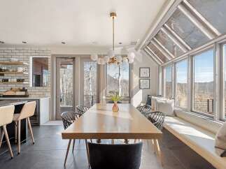 Experience breathtaking mountain views from this stunning dining area, featuring a large wooden table perfect for gatherings.