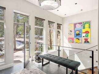 Step into this bright and airy entryway, featuring a modern tufted bench and a striking contemporary art piece.