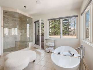 Indulge in luxury in this stunning master bathroom, featuring a spacious glass-enclosed shower with stone tile and a built-in bench.