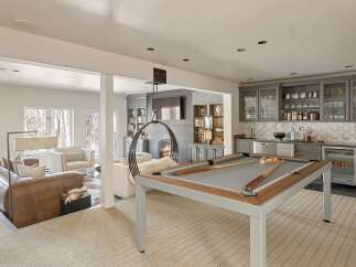 Experience ultimate entertainment in this luxurious basement featuring a modern pool table and a stylish bar area with ample glass storage.