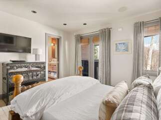 Experience ultimate comfort in this luxurious bedroom featuring a plush king-sized bed adorned with crisp white linens and decorative pillows.