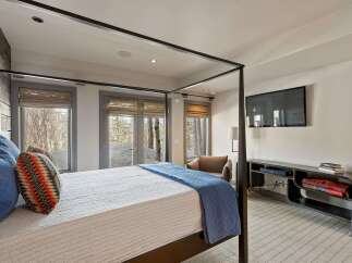 Experience ultimate comfort in this luxurious bedroom featuring a stylish four-poster bed adorned with plush blue and patterned pillows.
