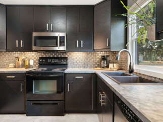 Discover this modern kitchen featuring sleek, dark wood cabinetry and a stylish mosaic tile backsplash.