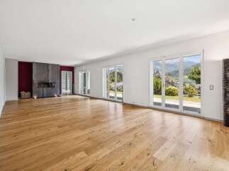 Experience modern living in this spacious great room featuring a sleek fireplace and expansive floor-to-ceiling windows that offer breathtaking mountain views.