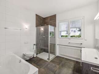 This modern bathroom features a spacious bathtub, a separate glass-enclosed shower, and a wall-mounted toilet.