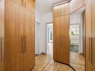 Discover modern living with this spacious hallway featuring sleek, floor-to-ceiling wooden wardrobes offering ample storage.