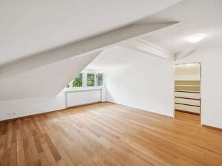 Discover this charming attic room featuring a beautiful hardwood floor and a large window that floods the space with natural light.