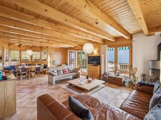 Experience cozy living in this charming wooden cabin featuring a spacious living area with a large sectional sofa and a modern fireplace.
