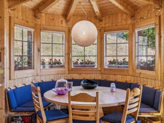 Enjoy cozy meals in this charming dining nook, featuring a round wooden table surrounded by a comfortable built-in banquette with vibrant blue cushions.