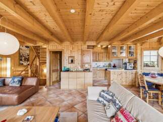Experience rustic charm in this beautifully appointed wooden cabin, featuring a spacious living area with a cozy leather sofa and a fully equipped kitchen with ample cabinetry.