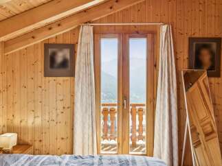 Experience breathtaking mountain views from this charming wooden cabin bedroom.