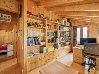 This charming wooden cabin features a cozy study area with extensive built-in bookshelves, perfect for organizing your collection.