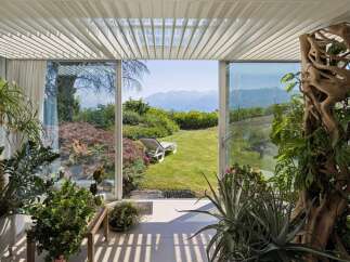 Experience seamless indoor-outdoor living with this stunning property, featuring expansive glass doors that open onto a lush garden and breathtaking mountain views.