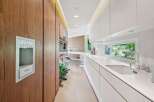 Experience modern luxury in this sleek kitchen, featuring rich wood cabinetry and pristine white countertops.