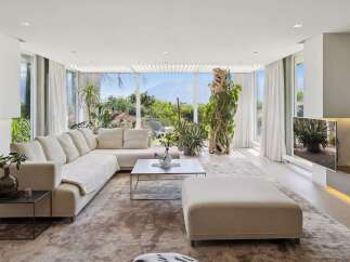 Experience luxurious living in this spacious modern living room, featuring a large sectional sofa and an ottoman perfect for relaxation.