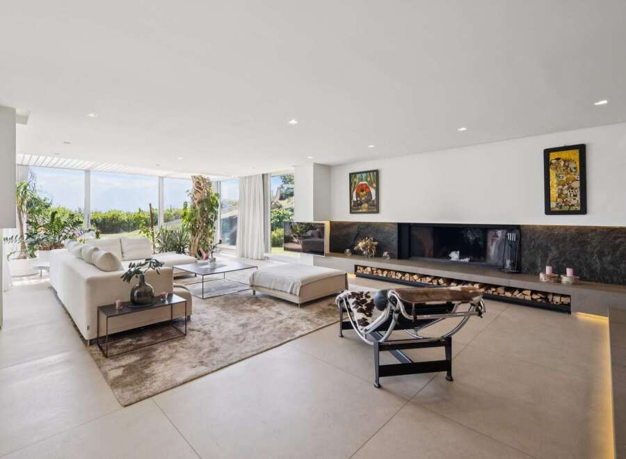 Experience modern luxury in this spacious living room, featuring a large sectional sofa and a striking linear fireplace with ample wood storage.