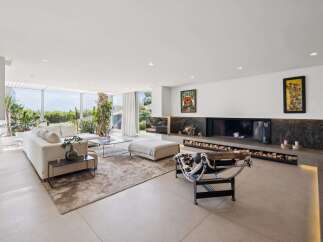 Experience modern luxury in this spacious living room, featuring a large sectional sofa and a striking linear fireplace with ample wood storage.