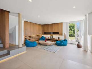 Experience modern living in this spacious living room featuring a stunning wooden accent wall with integrated shelving and a unique wine rack display.