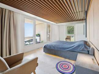 Experience modern luxury in this stunning bedroom featuring a king-size bed with a quilted blue comforter and ambient under-bed lighting.