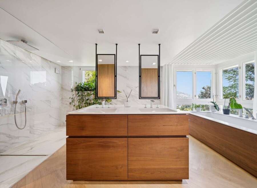Experience luxury in this stunning modern bathroom featuring a spacious walk-in shower with marble tile and a sleek rainfall showerhead.