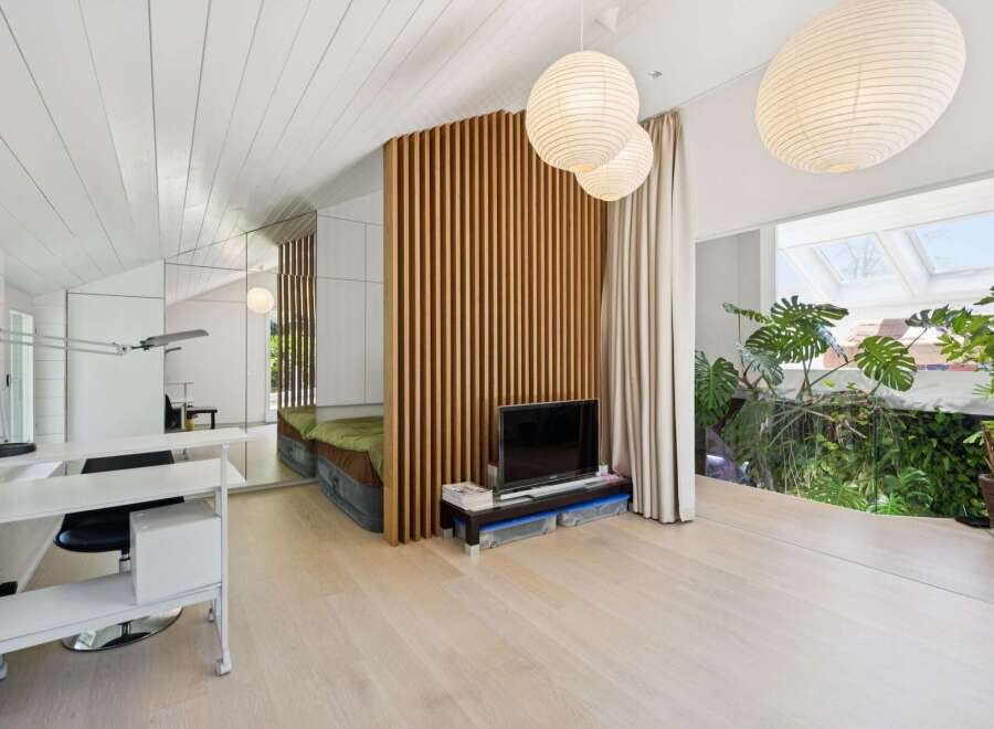This unique loft-style living space features a striking slatted wood divider, creating distinct zones for relaxation and work.