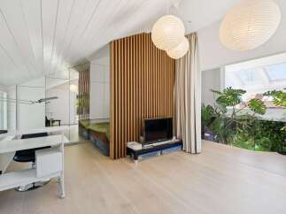 This unique loft-style living space features a striking slatted wood divider, creating distinct zones for relaxation and work.