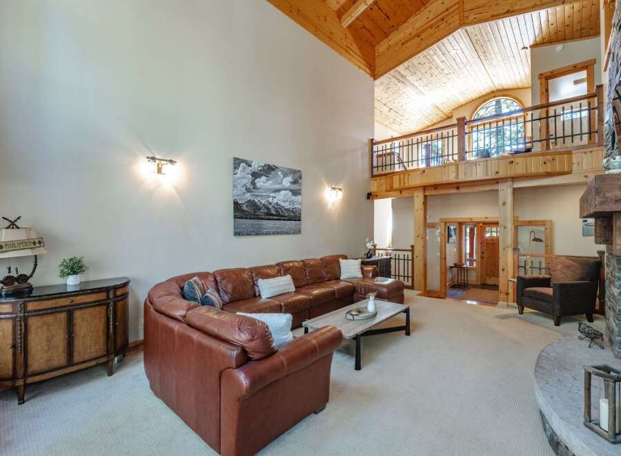 Experience luxury mountain living in this stunning great room, featuring a soaring vaulted wood-beamed ceiling and a grand stone fireplace.