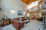 Experience luxury mountain living in this stunning great room, featuring a soaring vaulted wood-beamed ceiling and a grand stone fireplace.