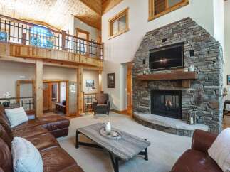 Experience rustic luxury in this stunning living room, featuring a grand stone fireplace as the centerpiece.