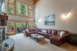 Experience breathtaking mountain views from this stunning living room, featuring a massive arched window and a cozy stone fireplace.