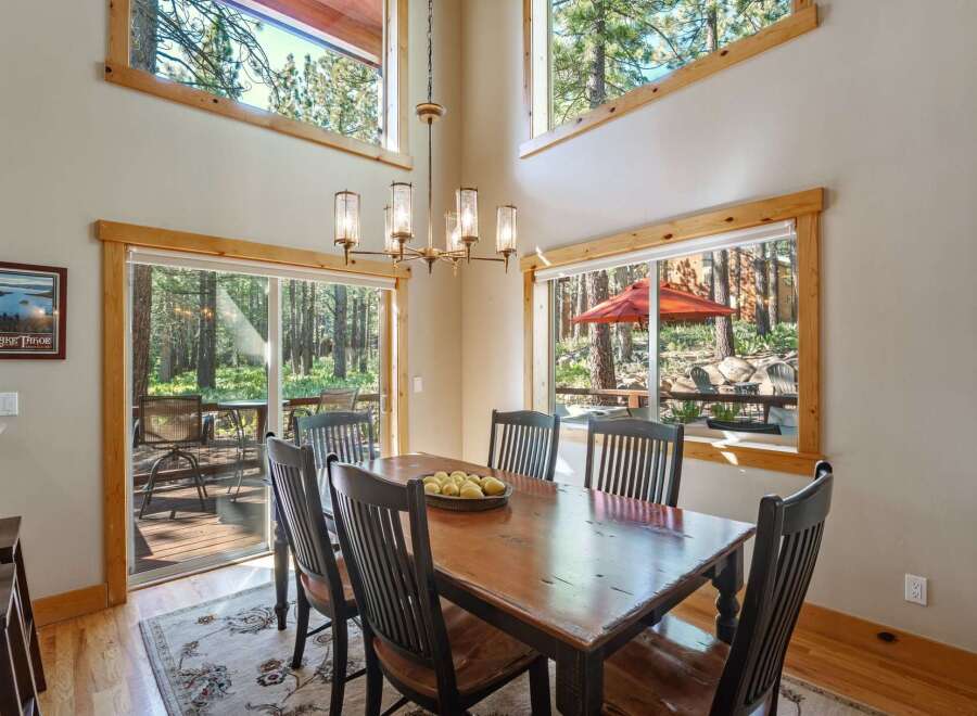 Experience breathtaking forest views from this stunning dining area, featuring a large wooden table perfect for gatherings.