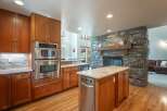 Experience luxury and comfort in this stunning kitchen, featuring a stacked stone fireplace as a captivating centerpiece.