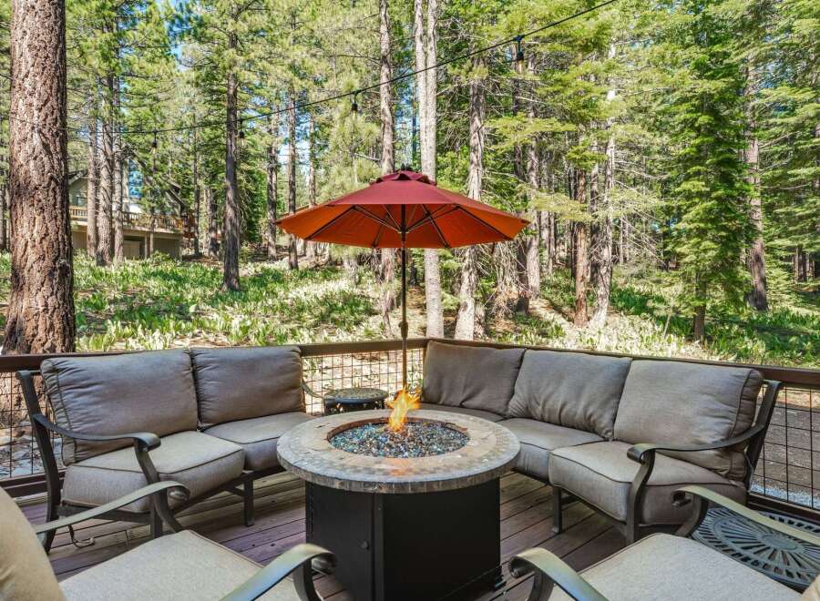 Enjoy the serene mountain setting from this inviting outdoor living space, complete with a cozy sectional sofa and a central fire pit perfect for cool evenings.