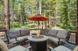 Enjoy the serene mountain setting from this inviting outdoor living space, complete with a cozy sectional sofa and a central fire pit perfect for cool evenings.
