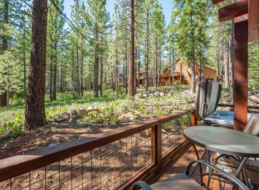 Enjoy the serene mountain lifestyle from this charming cabin deck, complete with a relaxing hot tub and outdoor seating area.