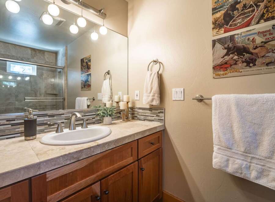 This charming bathroom features a spacious vanity with a stone countertop and a modern undermount sink, complemented by a decorative tile backsplash.