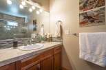 This charming bathroom features a spacious vanity with a stone countertop and a modern undermount sink, complemented by a decorative tile backsplash.
