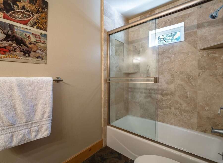 This bathroom features a stylish shower and tub combination with elegant travertine tile surround.