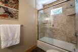 This bathroom features a stylish shower and tub combination with elegant travertine tile surround.