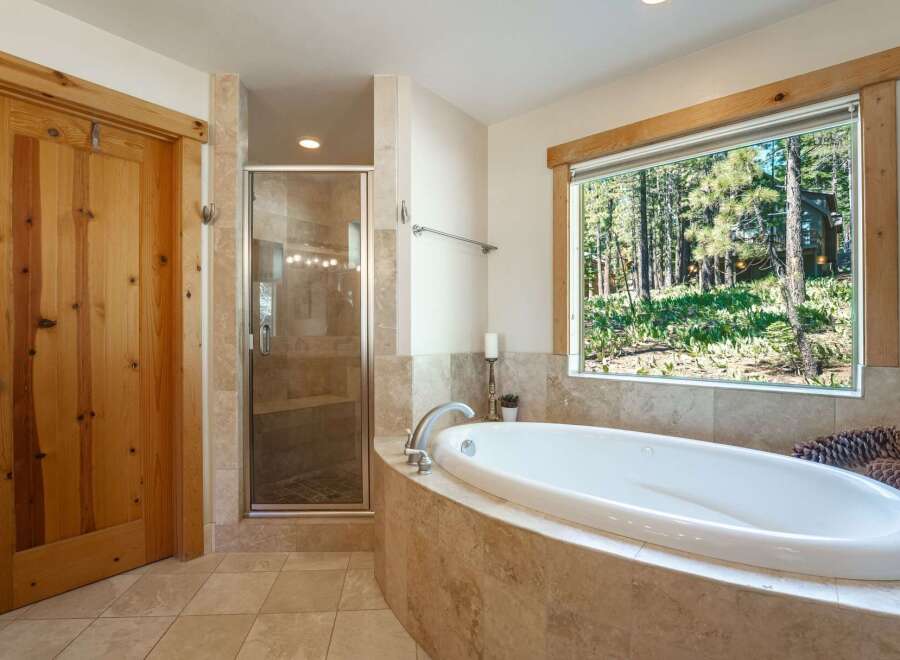 Indulge in relaxation in this luxurious bathroom featuring a spacious soaking tub with a stunning forest view.